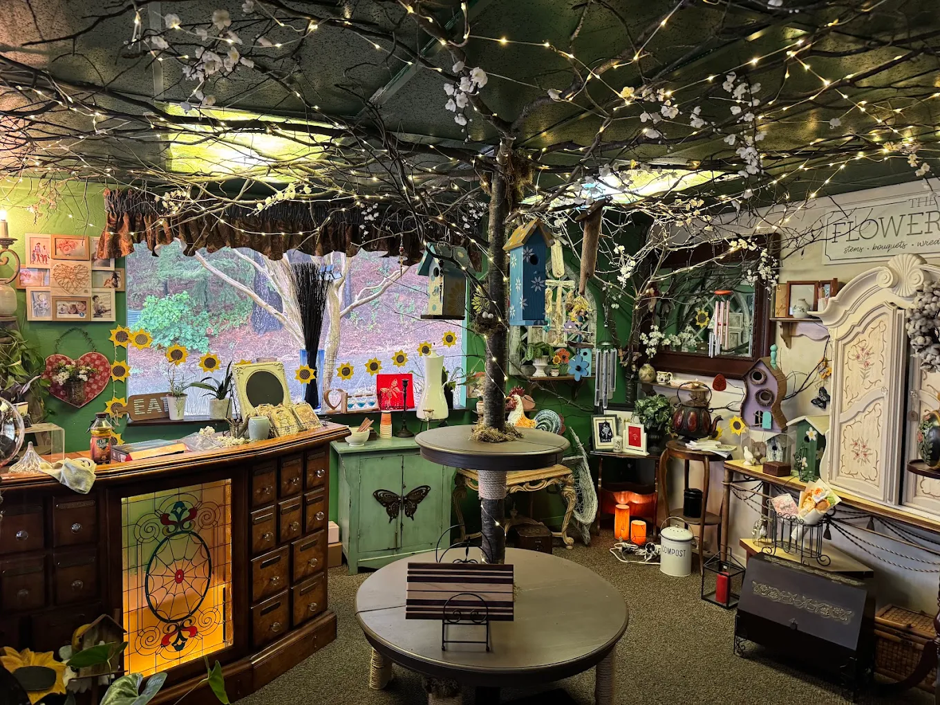Inside Enchanted Garden Shop, with twinkle lights overhead and the shop's centerpiece tree
